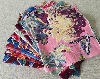 May include: A stack of fabric squares with floral and butterfly patterns in shades of pink, blue, red, and green.