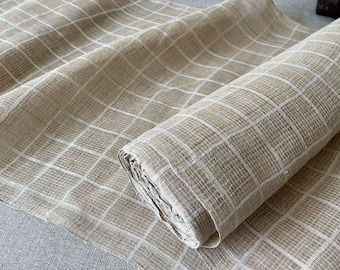 May include: A roll of beige fabric with a white checkered pattern. The fabric is woven and has a slightly rough texture.