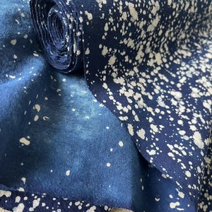 May include: A roll of blue fabric with white splatter paint. The fabric is folded in half and the roll is partially unrolled.
