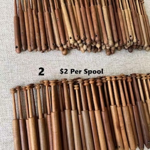 May include: A collection of wooden spools in varying shades of brown. The image is divided into two sections, with the text "1 $1 Per Spool" at the top and "2 $2 Per Spool" at the bottom. The spools are cylindrical with a rounded top.