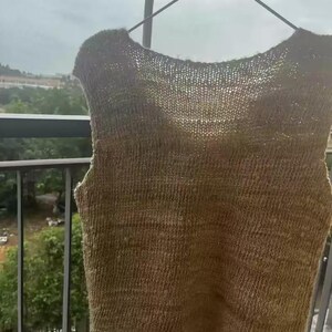 May include: A sleeveless knitted top in a light brown color. The top is made of a soft, textured yarn and has a relaxed fit.