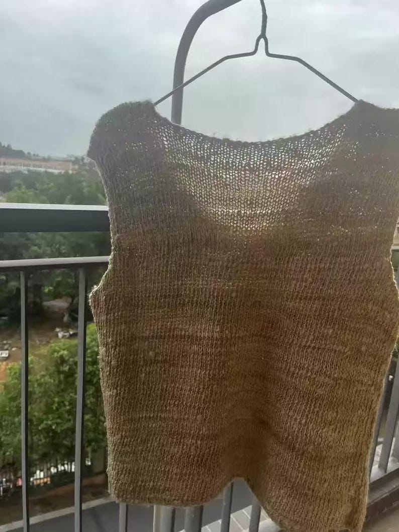 May include: A sleeveless knitted top in a light brown color. The top is made of a soft, textured yarn and has a relaxed fit.