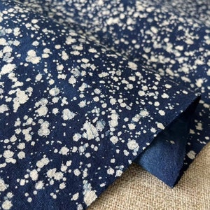 May include: A close-up of a dark blue fabric with a white splatter pattern. The fabric is folded over and the edges are visible.