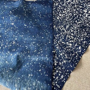 May include: Two pieces of blue fabric with a white splatter pattern. The fabric is folded and the white splatter pattern is more dense on one piece of fabric than the other.