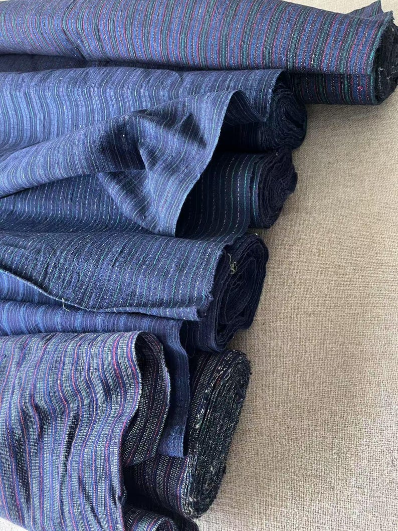 May include: A stack of blue and white striped fabric rolls. The fabric has a subtle shimmer and is perfect for crafting or sewing projects.