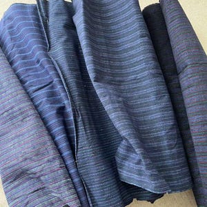 May include: Four pieces of blue and black striped fabric with a subtle sheen. The fabric is folded and arranged in a pile.