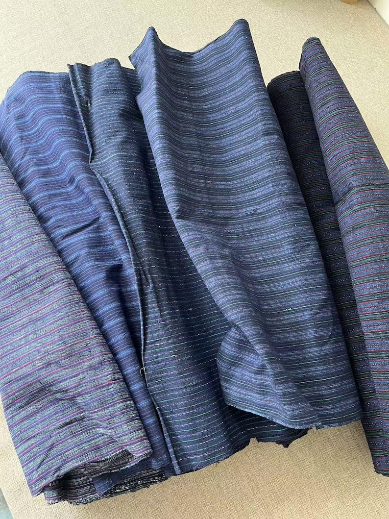 May include: Four pieces of blue and black striped fabric with a subtle sheen. The fabric is folded and arranged in a pile.