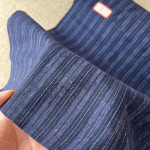 May include: A close-up of a blue and white striped fabric with a label that says "#2 59cm in width".