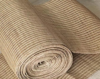 May include: A roll of natural fiber rug material with a striped pattern. The material is rolled up and the end of the roll is visible.
