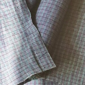 May include: Two pieces of fabric folded together, both are a light blue and dark gray plaid pattern.