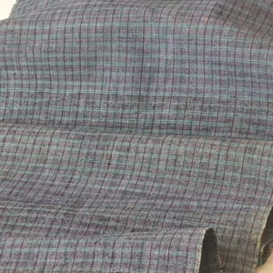May include: A close-up of a gray and blue checkered fabric. The fabric has a subtle sheen and a soft texture.