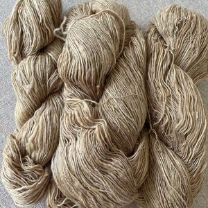 May include: A skein of natural colored yarn with a subtle fleck of brown. The yarn is made of a soft, natural fiber and is perfect for knitting or crocheting.
