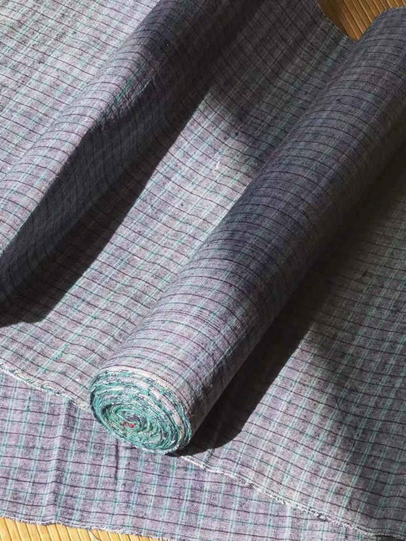 May include: A roll of blue and green checkered fabric. The fabric is woven with a fine, textured pattern.