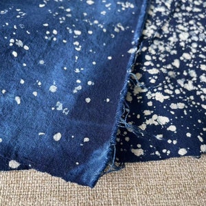 May include: Two pieces of blue fabric with a white splatter pattern. The fabric is folded over and the edges are frayed.