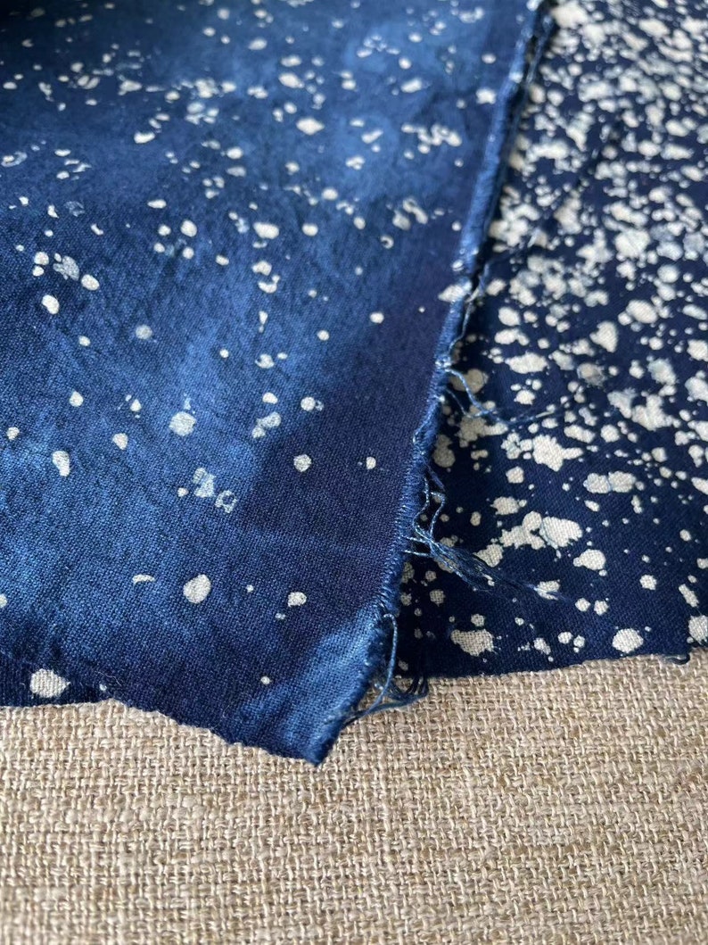 May include: Two pieces of blue fabric with a white splatter pattern. The fabric is folded over and the edges are frayed.