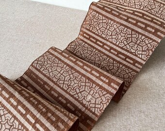Peut inclure: Un tissu à motifs géométriques brun et blanc. Le tissu est plié et a une surface texturée.