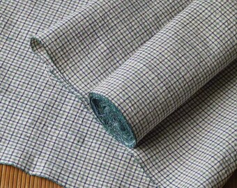 May include: A roll of white fabric with a green and blue checkered pattern. The fabric is folded in half and the end of the roll is visible.