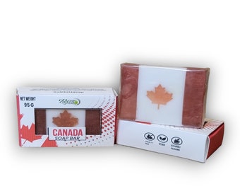 May include: A red, white, and brown soap bar with a Canadian flag design. The soap bar is packaged in a white box with red polka dots and the words "Canada Soap Bar". The box also has a green leaf logo and the words "Net Weight 95g".