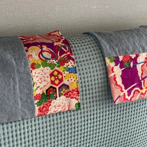 May include: Two gray linen throw pillows with colorful Japanese fabric panels. The fabric panels feature floral and geometric patterns in shades of pink, red, yellow, green, and purple.