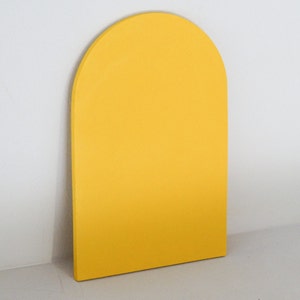Puede incluir: Una decoración de pared de madera en forma de arco de color amarillo. El arco es una forma simple con una superficie lisa.