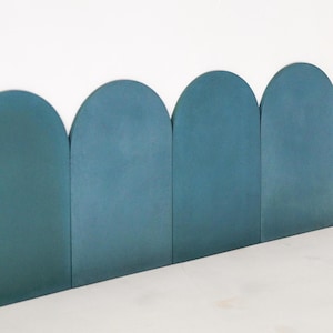 Puede incluir: Una fila de cinco azulejos de cerámica arqueados de color azul verdoso dispuestos en un patrón festoneado.