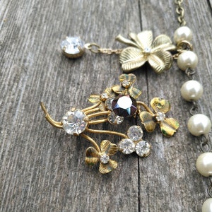 May include: A gold-tone necklace with a pearl strand and a charm featuring a cluster of shamrocks with clear and dark rhinestones.
