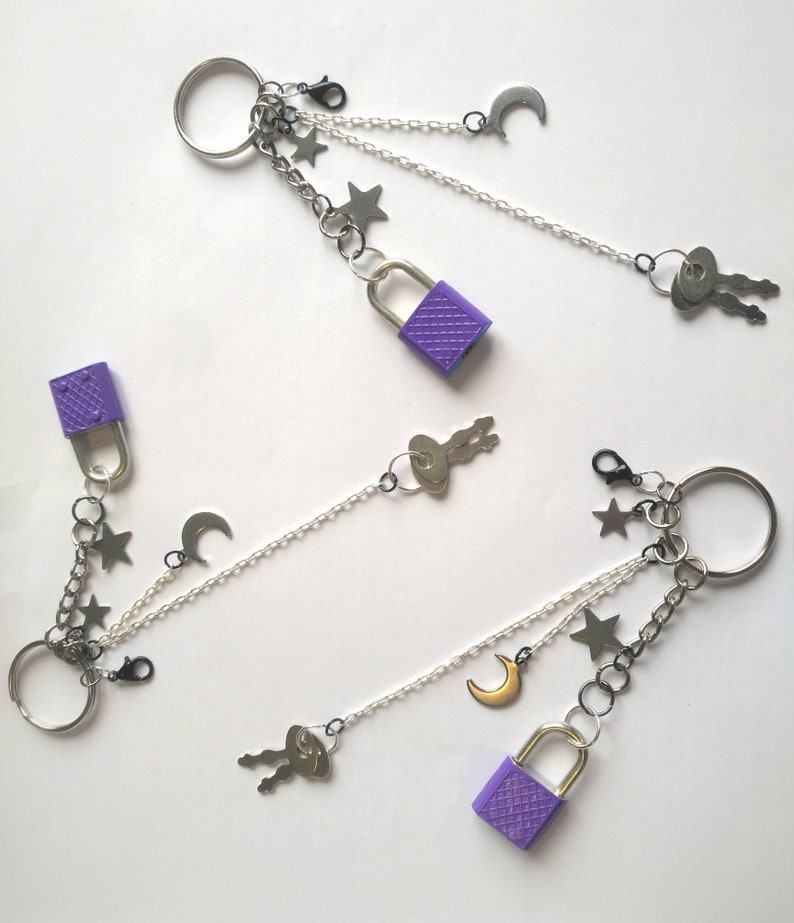 May include: Two purple lock and key charm keychains with silver chains, stars, moons, and key charms.