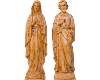 May include: Two wooden statues of religious figures. One statue depicts a woman with hands clasped in prayer, a rosary, and a draped robe. The other statue is of a man holding a staff and flowers, with a beard and flowing robes.
