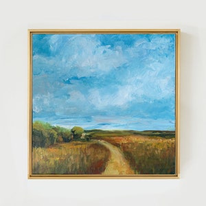 May include: A framed oil painting depicting a landscape with a dirt road leading through a field of tall grass. The sky is a bright blue with fluffy white clouds.