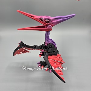 May include: A 3D printed skeletal model of a pterodactyl with red and purple paint. The wings are spread out and the head is tilted up. The model is on a white background.
