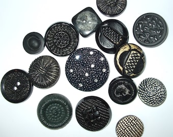 May include: A collection of 14 black and white buttons with various designs and textures. The buttons are arranged on a white surface.