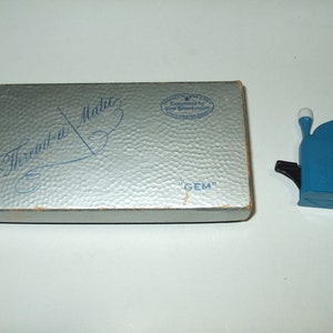 May include: A blue plastic thread-a-matic "GEM" sewing machine in its original box. The box is silver with blue lettering that reads "Thread-a-Matic" and "GEM".