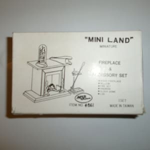 May include: A white box with a black and white illustration of a fireplace and accessories. The box is labeled "Mini Land" Miniature Fireplace & Accessory Set. The set includes a wood fireplace, bellows, fire set, andiron, clock dome, and log. Item number 4861. Made in Taiwan.