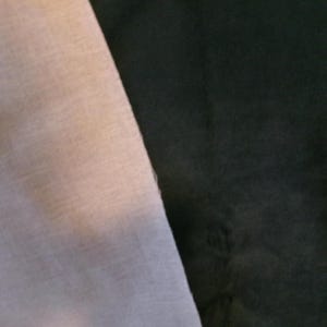 Może przedstawiać: Zbliżenie na dwa pr&oacute;bniki tkaniny, jeden jasnoszary, a drugi ciemnoszary. Pr&oacute;bniki są umieszczone obok siebie, pokazując r&oacute;żnicę w kolorze i fakturze.