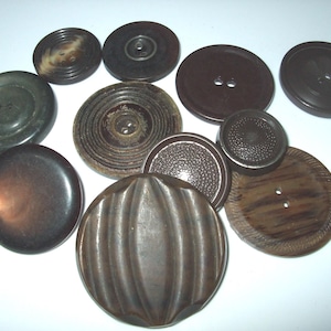 May include: Assortment of ten brown, black, and wood-toned buttons of various sizes and designs. Some buttons have a smooth finish, while others have a textured or patterned surface.
