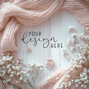 Könnte beinhalten: Ein weißer Holzgrund mit einem rosafarbenen Strickpullover und weißen Babyschnabelblumen. Der Text "YOUR design HERE" ist in Schwarz auf dem Holz geschrieben.