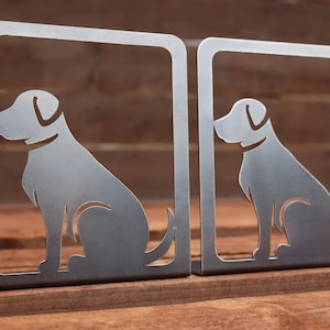 May include: A pair of metal bookends shaped like sitting dogs. The bookends are silver and have a simple silhouette design.