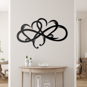 May include: Black metal wall decor with a swirling, abstract design. The decor is mounted on a white wall above a wooden console table.