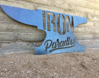 May include: A metal sign shaped like an anvil with the words "IRON Paradise" cut out. The sign is blue and the words are black.