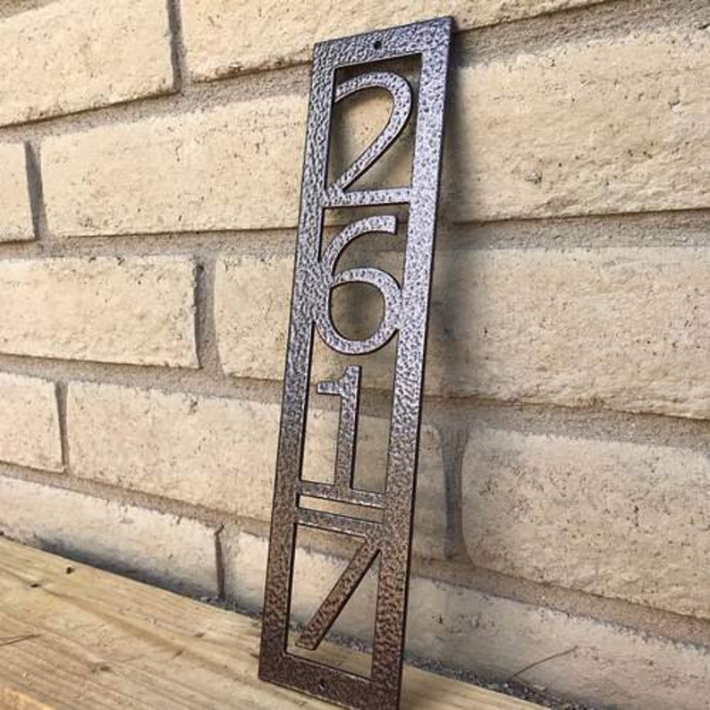 May include: A vertical metal house number sign with the number 2617 in a modern font. The sign is a dark brown colour with a textured finish.