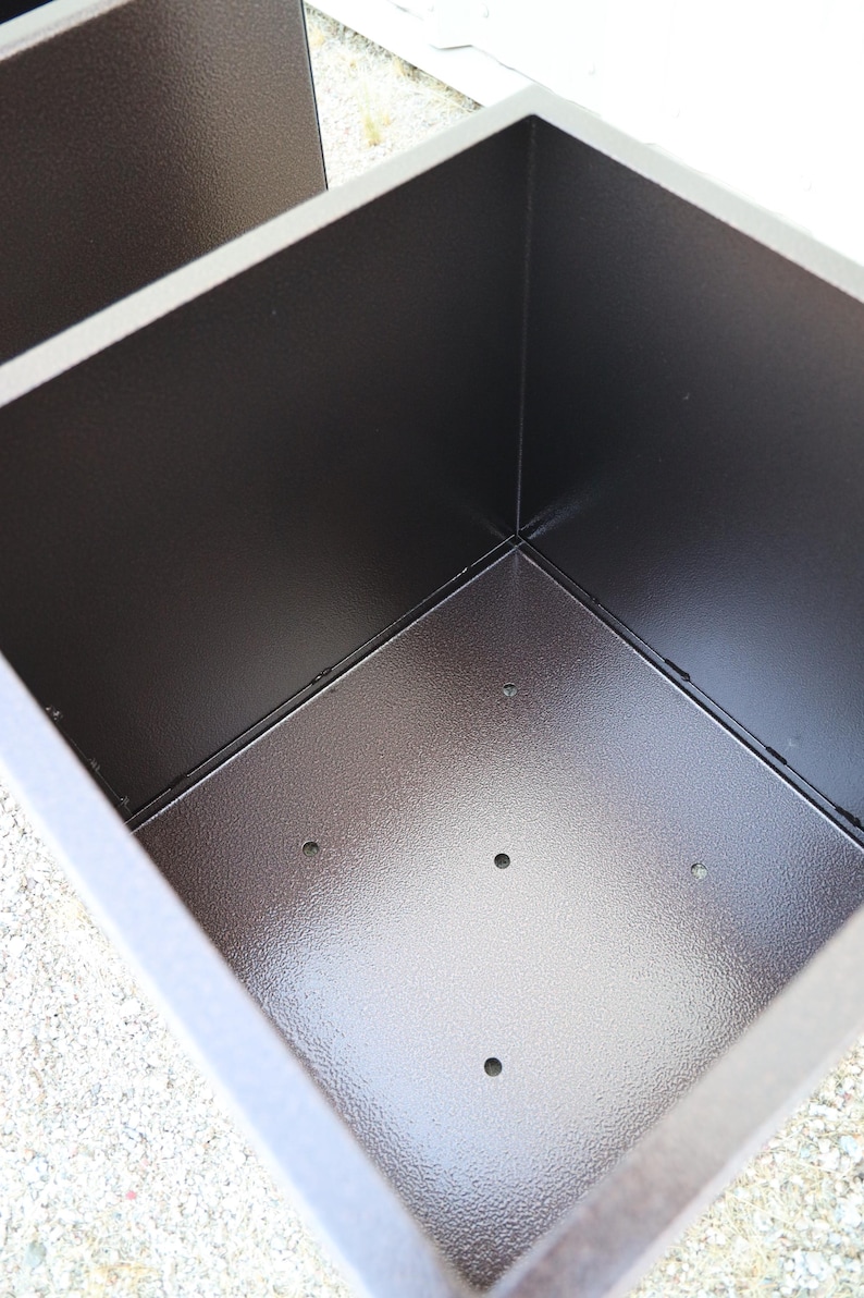 May include: A brown metal planter with a square shape and a textured finish. The planter has several drainage holes in the bottom.