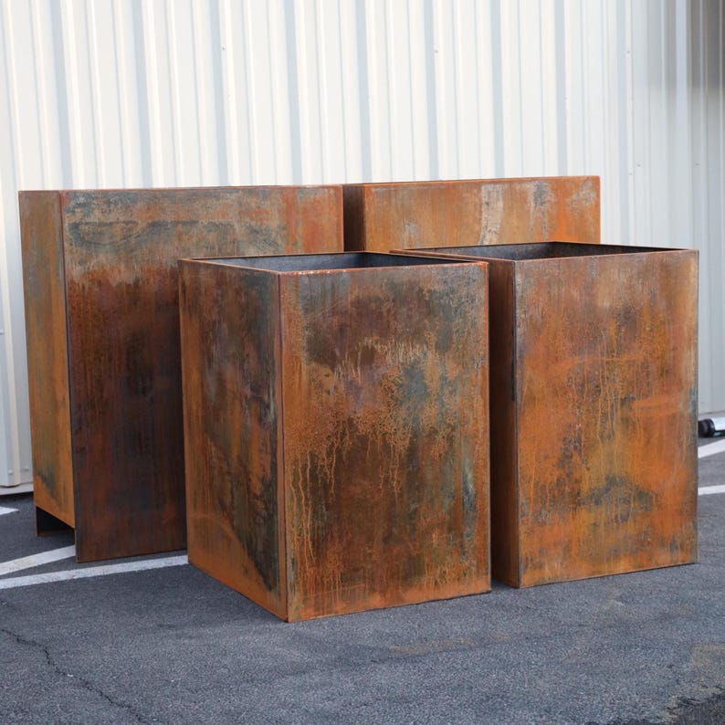 May include: Three rectangular metal planters with a rusted finish. The planters are different sizes and are arranged in a row.