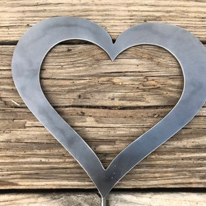 Pu&ograve; includere: Un ritaglio di metallo a forma di cuore su uno sfondo di legno rustico.