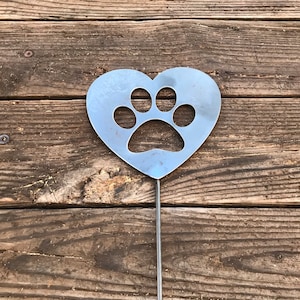 May include: A metal heart-shaped garden stake with a paw print cut out. The stake is silver and has a long, thin stem.
