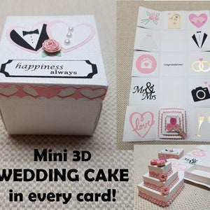 May include: A white box with a pink and white 3D wedding cake design. The box is decorated with hearts, flowers, and the words "happiness always". The box is open and the inside is decorated with a variety of wedding-themed images, including a bride and groom, a wedding ring, a house, and a camera.