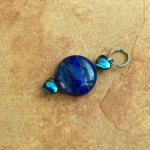 May include: A blue lapis lazuli gemstone pendant with two iridescent blue heart-shaped beads on a silver chain.
