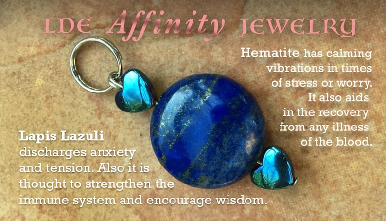 May include: A blue Lapis Lazuli stone pendant with silver accents and two teal heart-shaped charms. The pendant is on a brown background with text that reads "Lapis Lazuli discharges anxiety and tension. Also it is thought to strengthen the immune system and encourage wisdom." Hematite has calming vibrations in times of stress or worry. It also aids in the recovery from any illness of the blood.