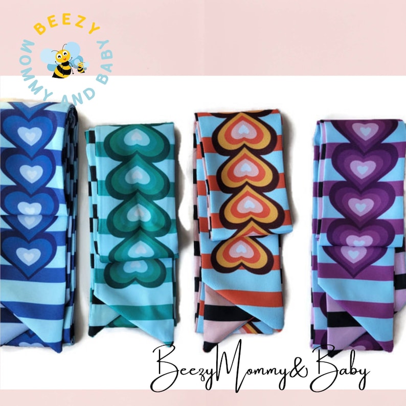 May include: Four fabric headbands with a blue, green, orange, and purple heart pattern. The headbands are striped with black and white.