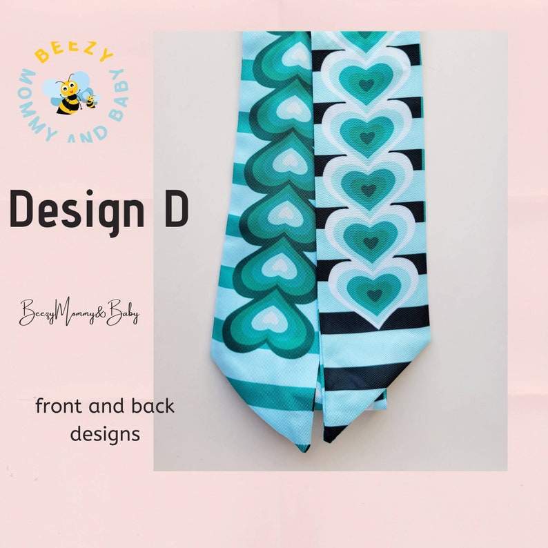 May include: A turquoise and white fabric headband with a design of concentric hearts on one side and black and white stripes on the other side. The headband is labeled "Beezy Mommy & Baby" and "Design D".