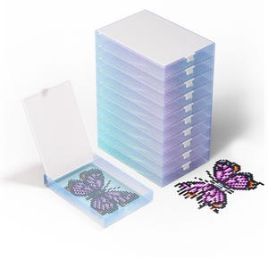 Peut inclure: Une pile de boîtes de rangement en plastique transparent avec un dégradé bleu et violet. Une boîte est ouverte, révélant un motif de papillon fait de petites perles colorées. Un motif de papillon terminé est à côté.